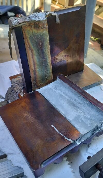 A fresh casting nearly released from the mould, with riser and overflow material still visible